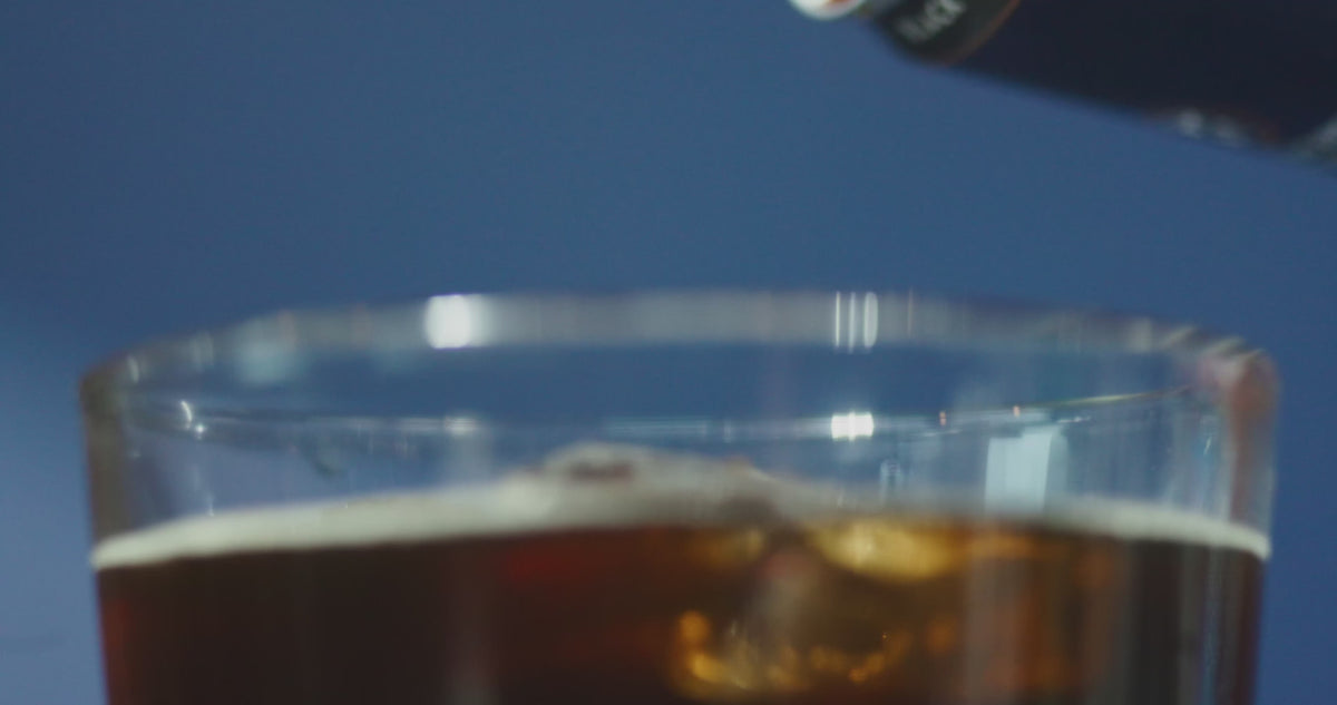 Cold brew pouring out of a can and into a full glass