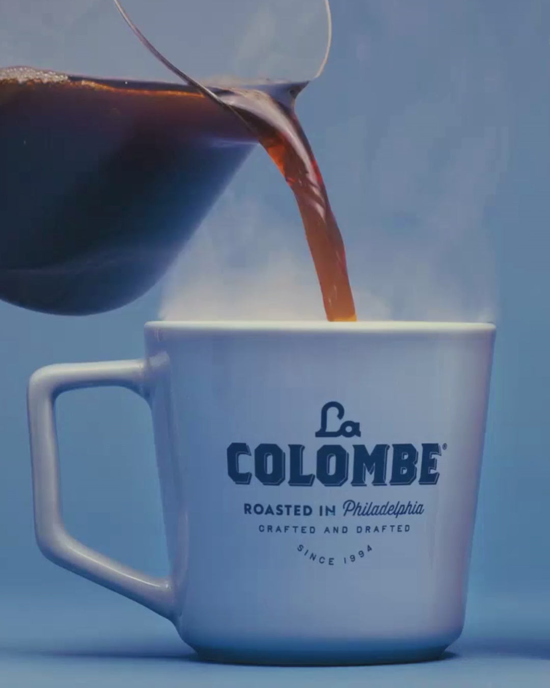 Hot coffee pouring into a light blue mug